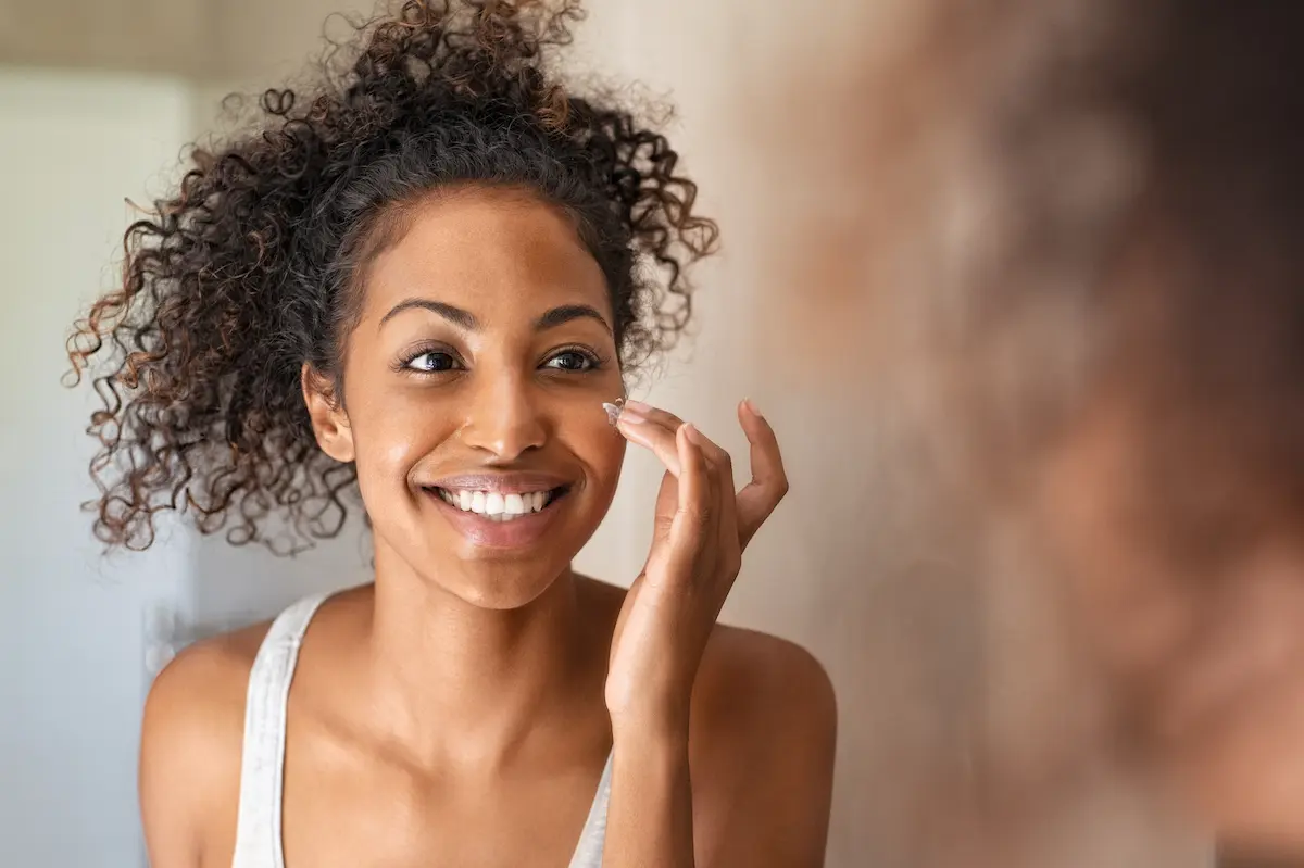 A woman applying topical cream to her face